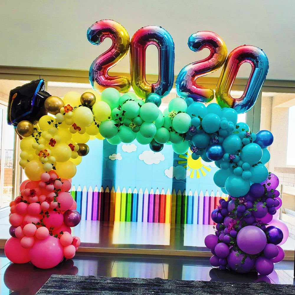 Colourful organic balloon arch framing a photo backdrop.