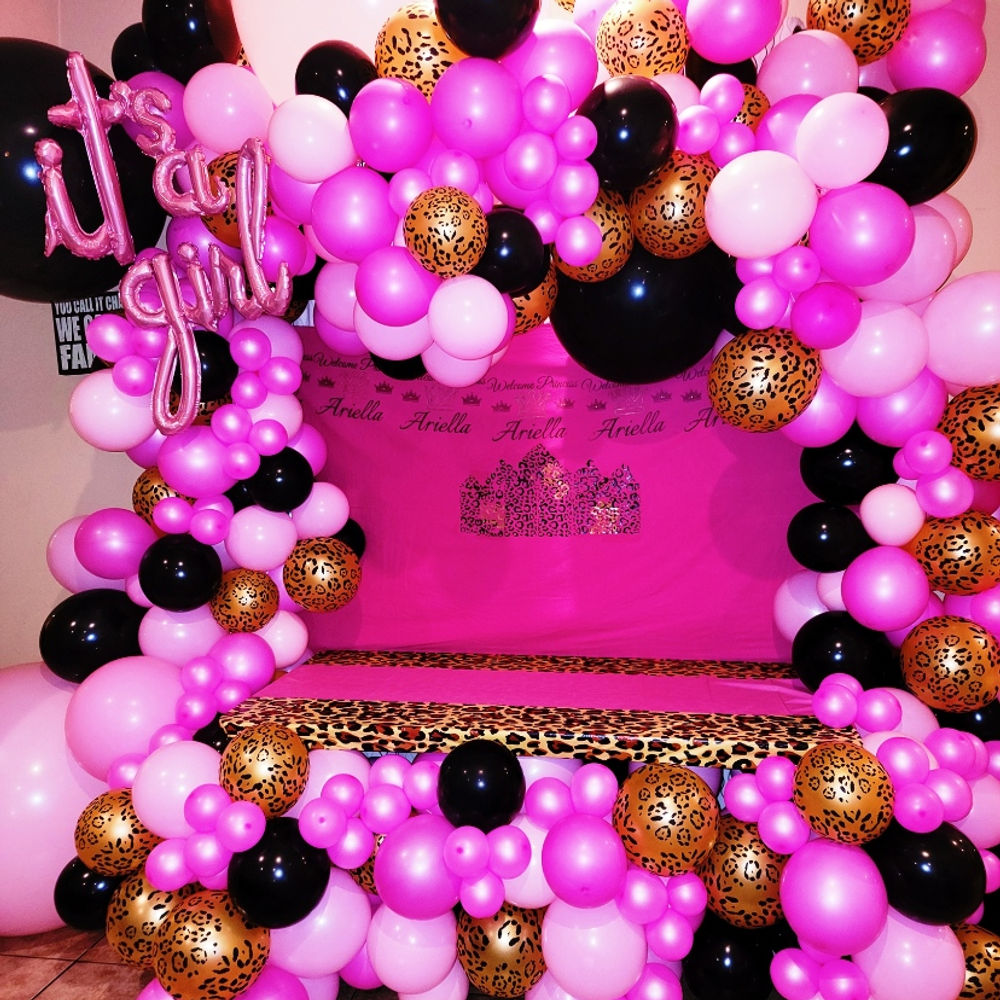Pink, black and leopard-print balloon installation framing a celebration backdrop.