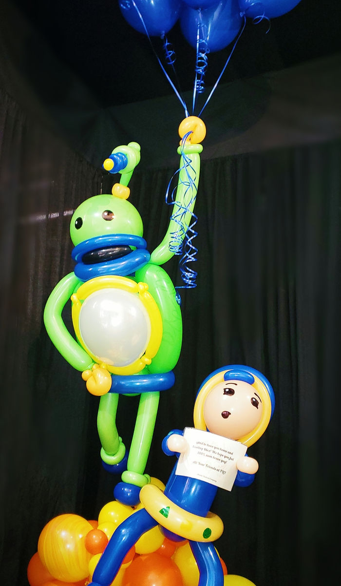 Custom balloon delivery bouquet featuring two character sculptures and a message tag.